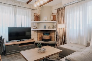 A living room with a flat-screen TV, a sofa, a coffee table, and a fireplace with decorative items.
