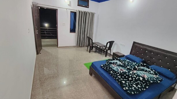 A bedroom with a bed, a desk, a chair, a ceiling fan, and a window with curtains. - rk tourist loge (Ukhimath)