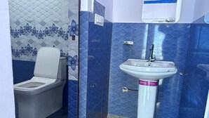 A bathroom with a toilet, a sink, and blue patterned walls. - rk tourist loge (Ukhimath)