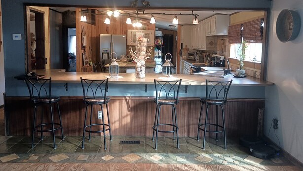 A kitchen with a bar area, wooden cabinets, and a large mirror. - Relaxing Beautiful Views Plenty of Back Roads to Ride ATVs-Horses- Pets Welcomed (Aiken)