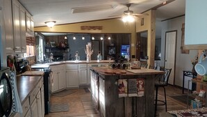 A kitchen with white cabinets, a wooden island, and a ceiling fan. - Relaxing Beautiful Views Plenty of Back Roads to Ride ATVs-Horses- Pets Welcomed (Aiken)