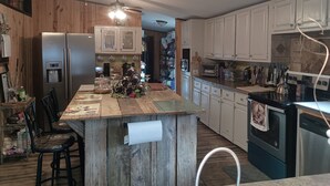 A kitchen with wooden cabinets, a central island, a refrigerator, a dishwasher, and a ceiling fan. - Relaxing Beautiful Views Plenty of Back Roads to Ride ATVs-Horses- Pets Welcomed (Aiken)