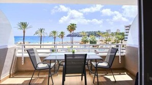 Ein Balkon mit Tisch und Stühlen mit Blick auf Strand und Stadtlandschaft.