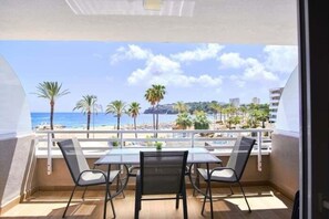 Ein Balkon mit Tisch und Stühlen mit Blick auf Strand und Stadtlandschaft.