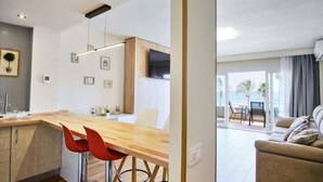 Eine moderne Küche mit Holzarbeitsplatte, roten Barhocker und einem Essbereich mit weißem Tisch und Stühlen.