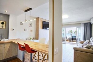 Eine moderne Küche mit Holzarbeitsplatte, roten Barhocker und einem Essbereich mit weißem Tisch und Stühlen.