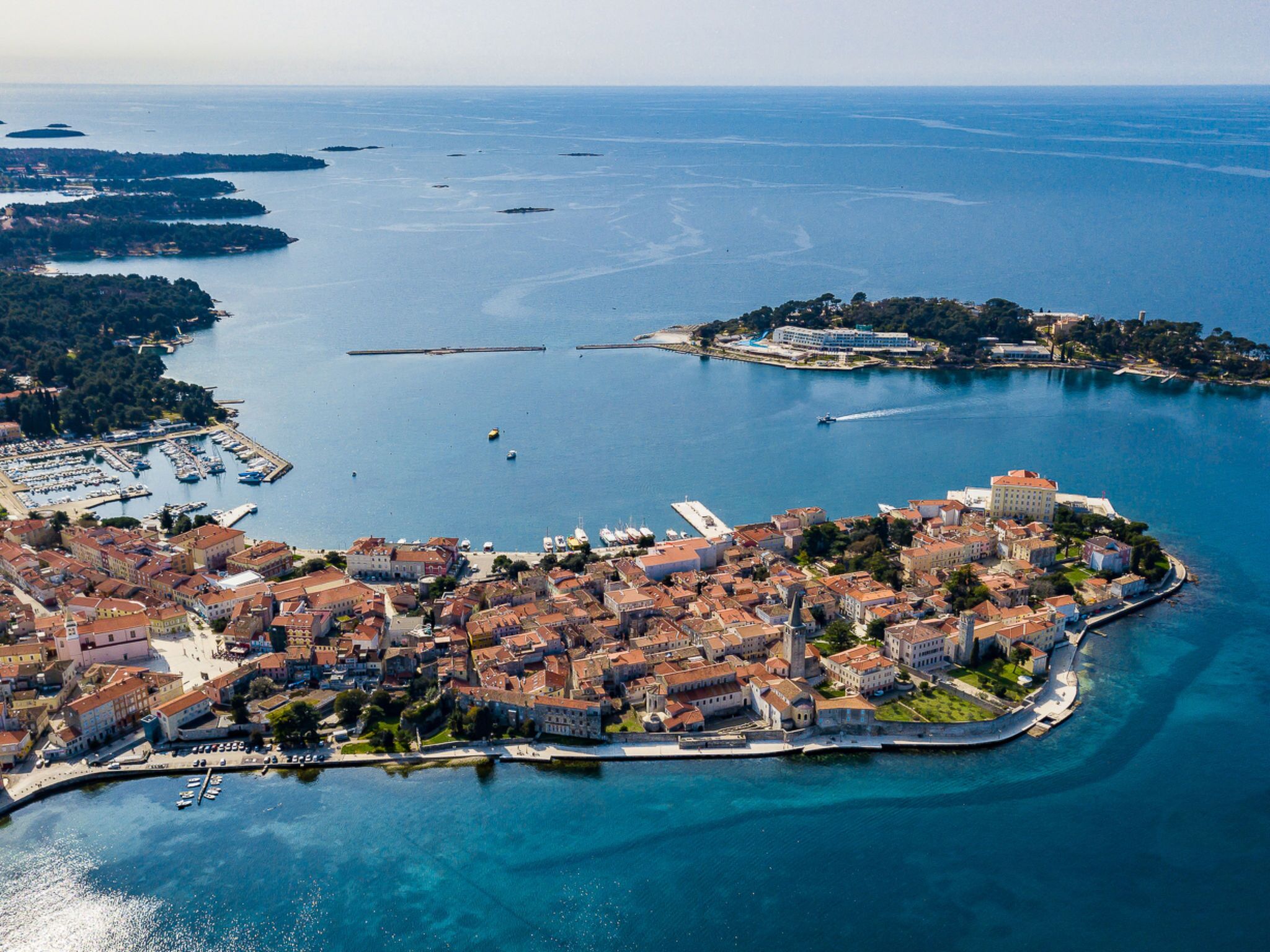 An aerial view of a coastal town with a marina, historic buildings, and a prominent castle-like structure.