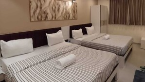 A hotel room with two beds, a ceiling fan, recessed lighting, a large abstract painting, and a wardrobe. - Lalji S Hotel And Restaurant (Ahmedabad)