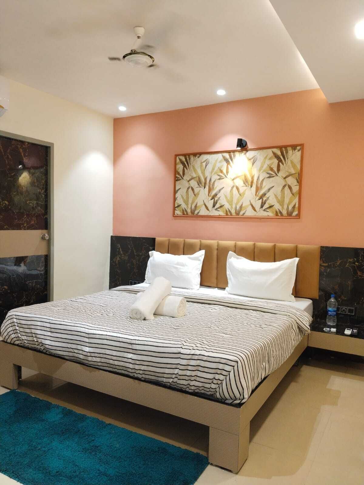 Una habitación de hotel moderna con una cama grande, un ventilador de techo, una lámpara montada en la pared e impresión botánica enmarcada.