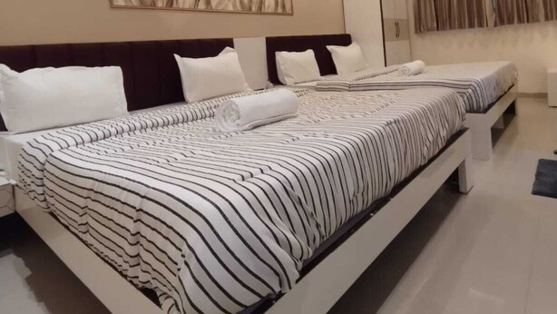 A modern hotel room with a large bed, bedside tables, a ceiling light, and a wall-mounted artwork. - Lalji S Hotel And Restaurant (Ahmedabad)
