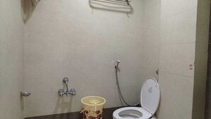 A small bathroom with a toilet, a shower, and a hand dryer. - Lalji S Hotel And Restaurant (Ahmedabad)