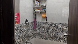 Un baño con ducha, inodoro, lavabo y estante con artículos de aseo.