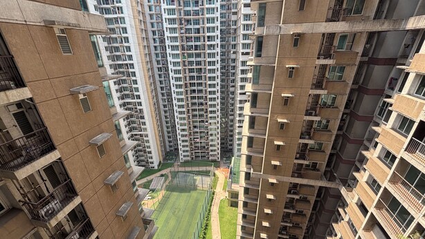 Un edificio residencial alto con varios balcones, un patio central y una cancha deportiva.