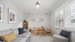 Un salon moderne avec un canapé gris, une table ronde et des chaises.