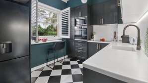 Une cuisine moderne avec un carrelage à motifs, une fenêtre avec des stores et un four encastré.