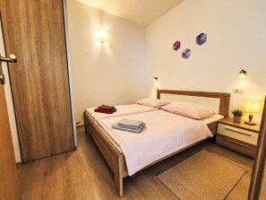 Ein Schlafzimmer mit einem hölzernen Bett, einem Nachttisch mit Lampe sowie einer Wandleuchte.
