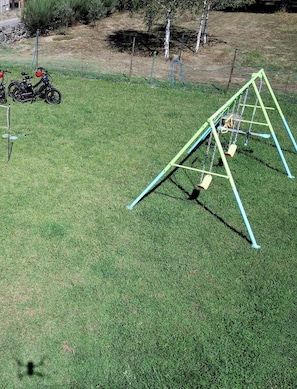 A grassy yard with a swing set and a bicycle.