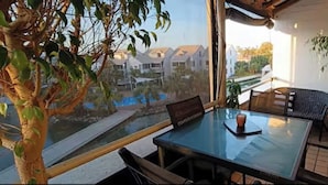 Un balcon avec une table en verre, des chaises et un pot de fleurs.