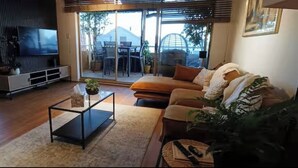 Un salon comprenant un canapé, une table basse, un téléviseur et une porte-fenêtre coulissante donnant sur un espace extérieur.
