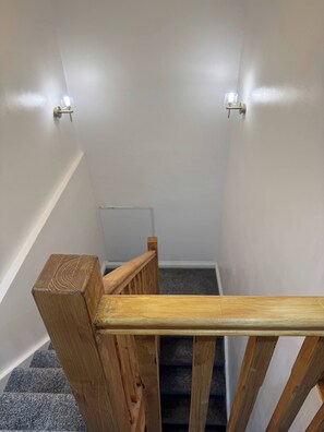 Una escalera con barandillas de madera y un rellano alfombrado.