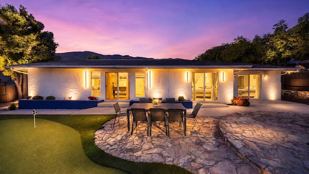 A modern house with a patio, a dining area, and a pool.