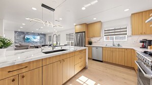 A modern kitchen with wooden cabinets, stainless steel appliances, and a marble countertop.