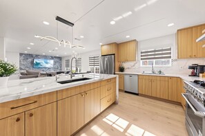 A modern kitchen with wooden cabinets, stainless steel appliances, and a marble countertop.