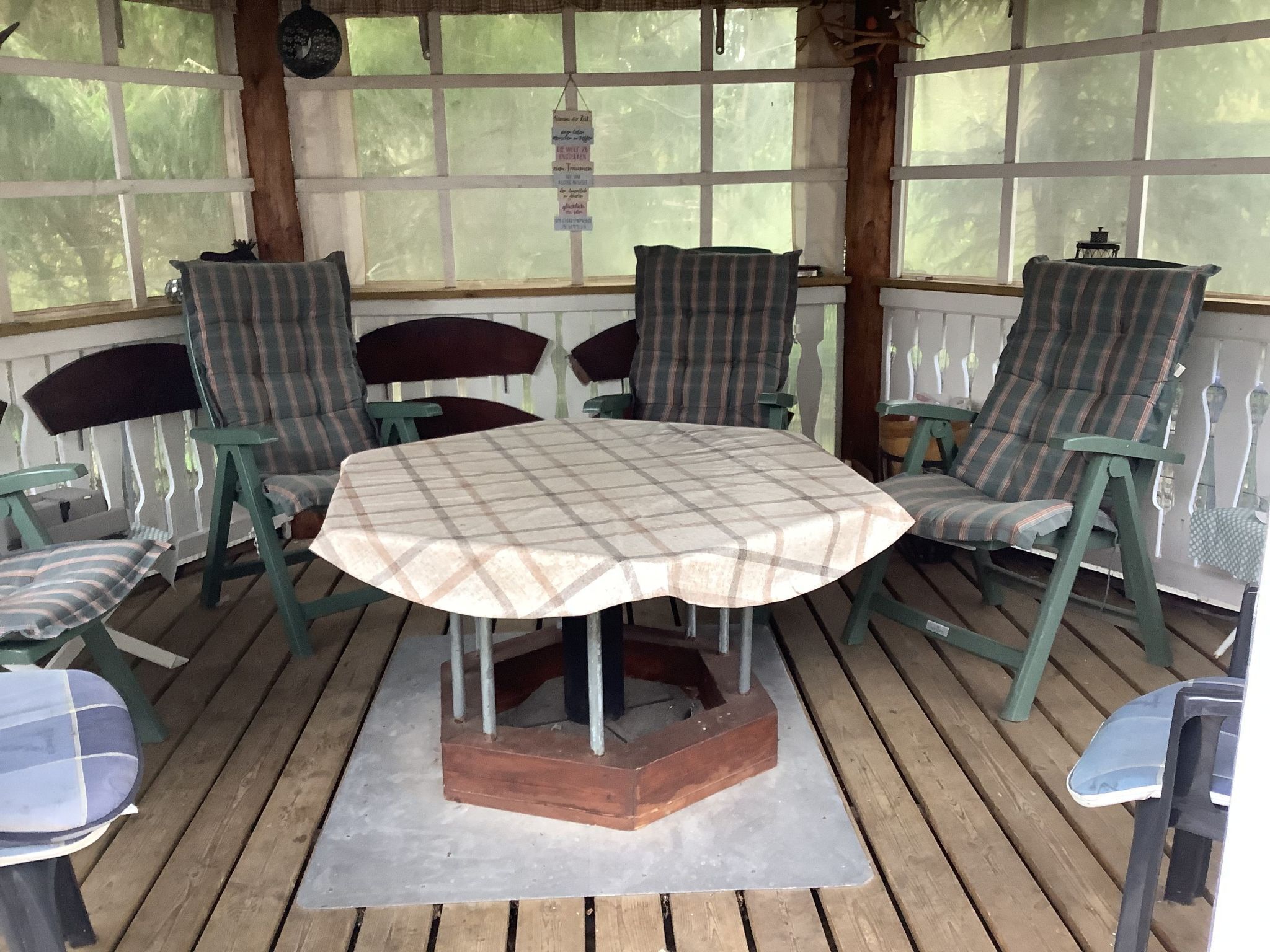 Une terrasse couverte avec une table ronde et quatre chaises.