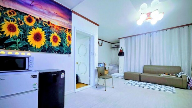 A living room with a sofa, a chair, a microwave, a refrigerator, and a painting of sunflowers. - 3BR Seongsu Station 3min walk Urban Cozy House2 (Seoul)
