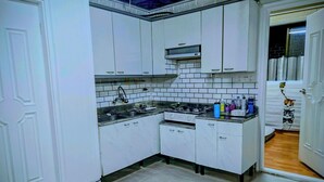 A kitchen with white cabinets, a stainless steel sink, and a microwave. - 3BR Seongsu Station 3min walk Urban Cozy House2 (Seoul)