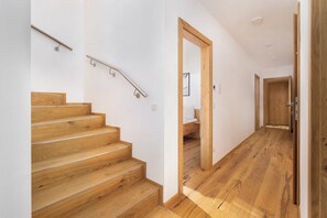 Eine Treppe mit Holzbalken und Metallgeländern, die zu einem Schlafzimmer mit Holztür und Bett führt.