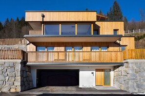 Ein modernes, mehrgeschossiges Gebäude mit Garage, Holzbalkonen und Steinwänden.