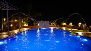 A nighttime swimming pool with water features and lights. - Swapnali Beach Resort (Murud)