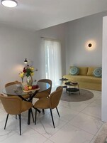 Una sala moderna con una mesa de comedor redonda de vidrio, dos sillas, un sofá y una mesa de centro.