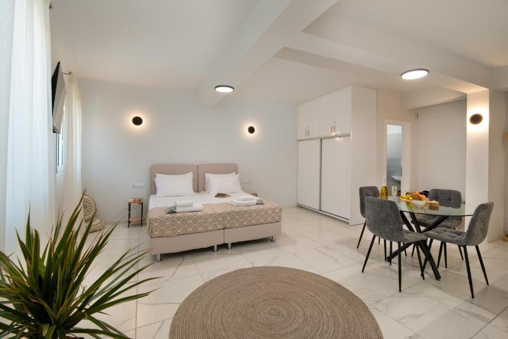 Un dormitorio moderno con cama, mesita de noche y un comedor con sillas y una mesa.