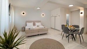 Quarto moderno com cama, mesa de cabeceira e um espaço de jantar com cadeiras e mesa.