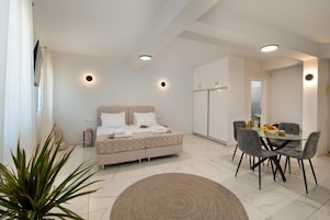 A modern bedroom with a bed, bedside table, and a dining area with chairs and a table.
