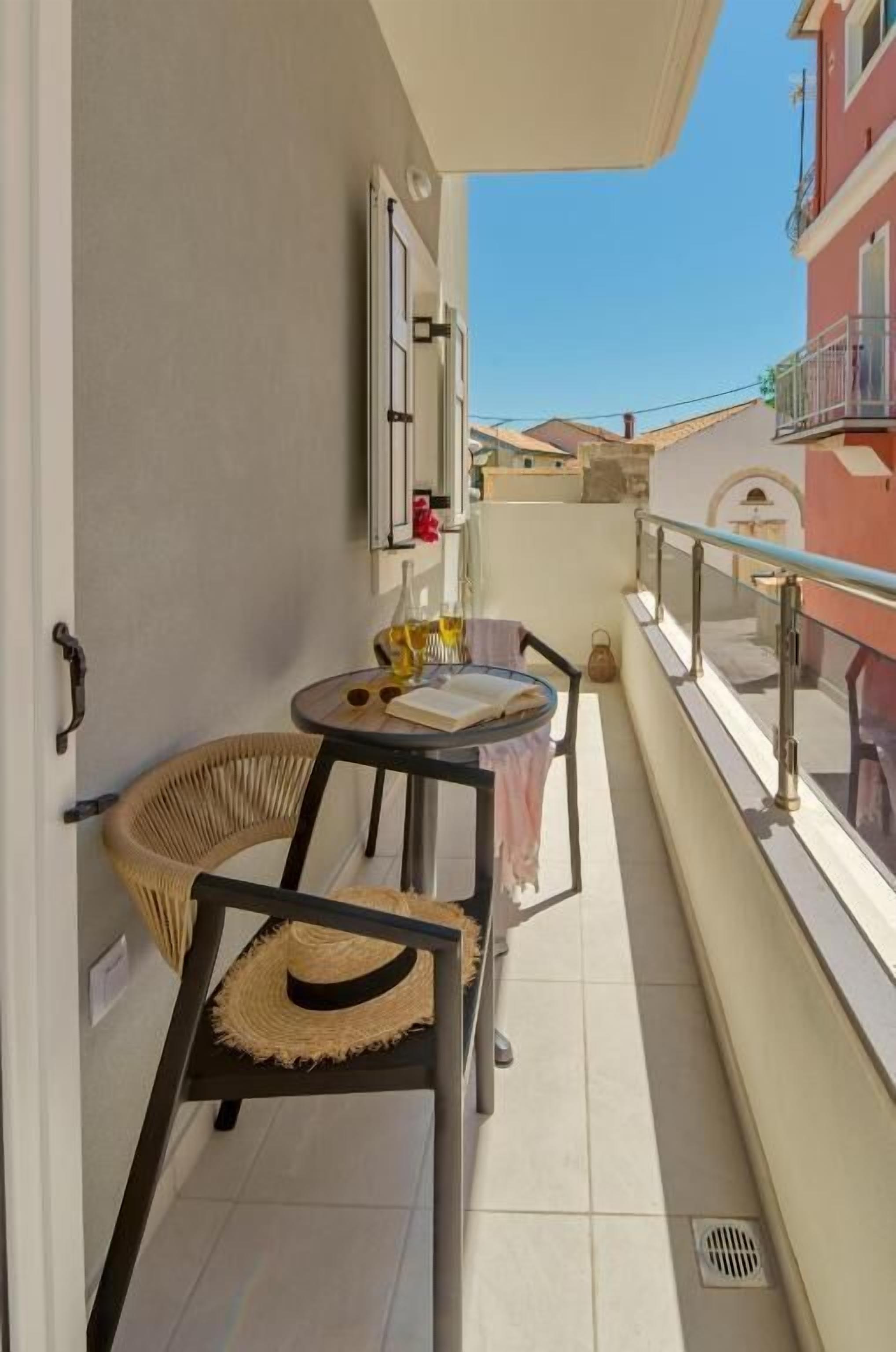 A balcony with a chair, a small table, and a window.