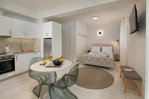Un espacio habitable compacto con kitchenette, comedor y dormitorio.
