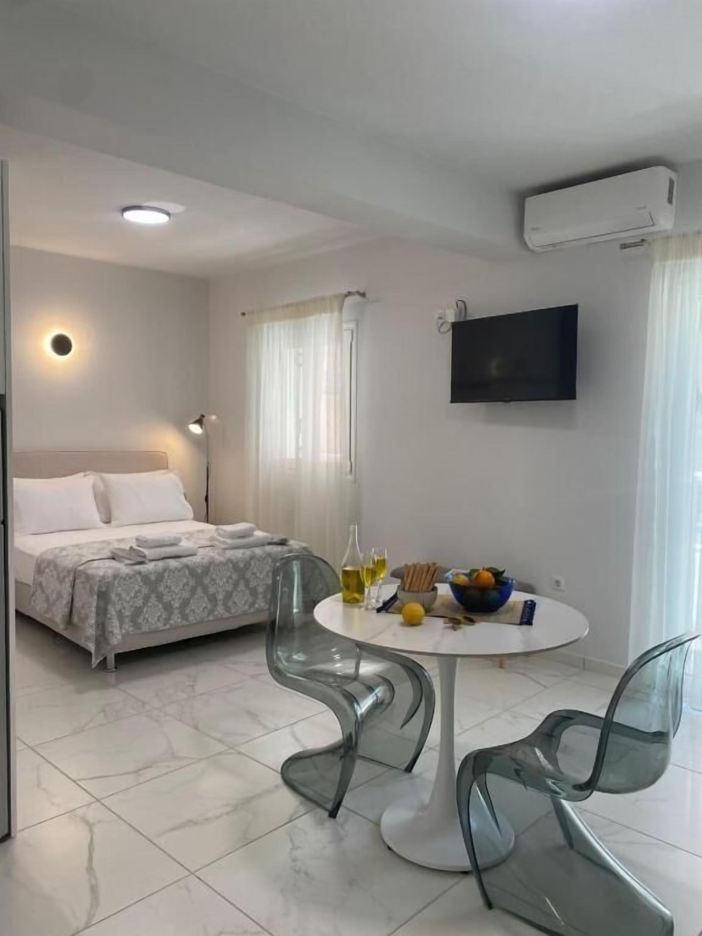 Een hotelkamer met een bed, een ronde tafel met stoelen, een televisie en een airconditioning.