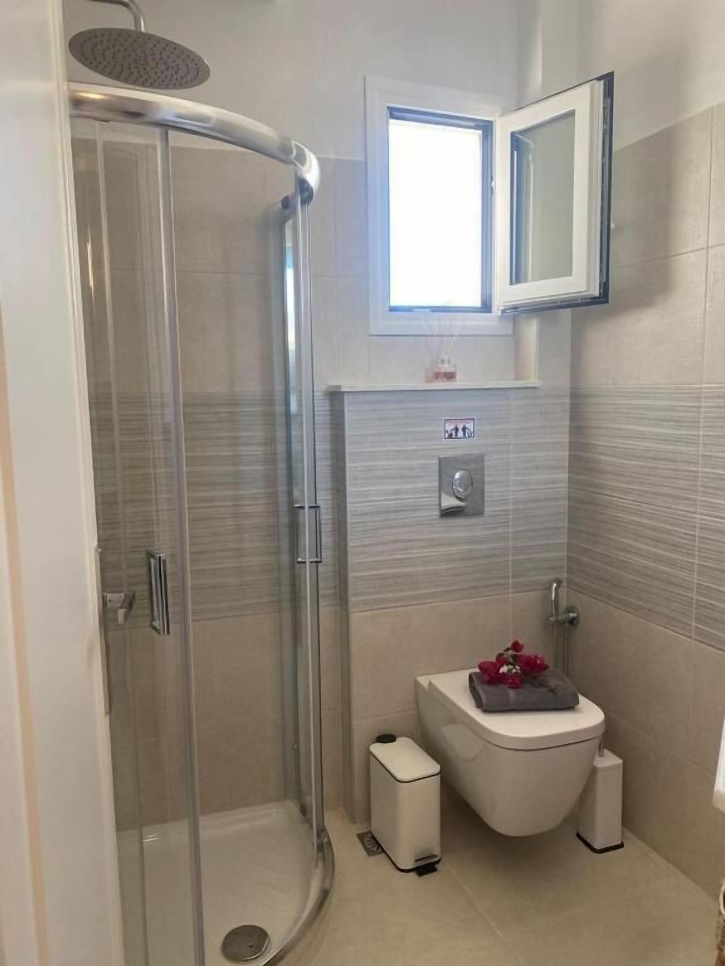 Un baño moderno con cabina de ducha de vidrio, inodoro y lavabo.