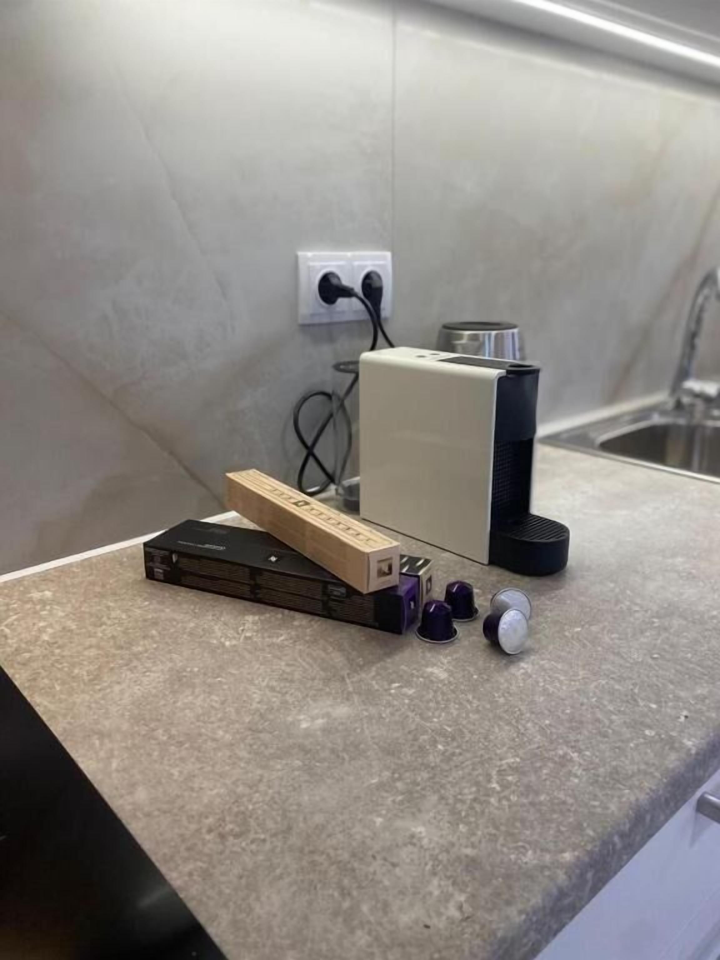 A kitchen counter with a power strip, a box, and two purple containers.