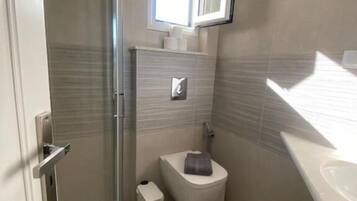 A bathroom with a shower, toilet, and sink.