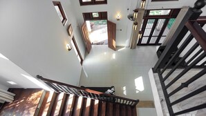 A staircase with wooden steps and a metal handrail, leading to a landing with a view of the outside. - Spacious 5-bedroom villa near Ragama Teaching Hospital (Kadawatha)