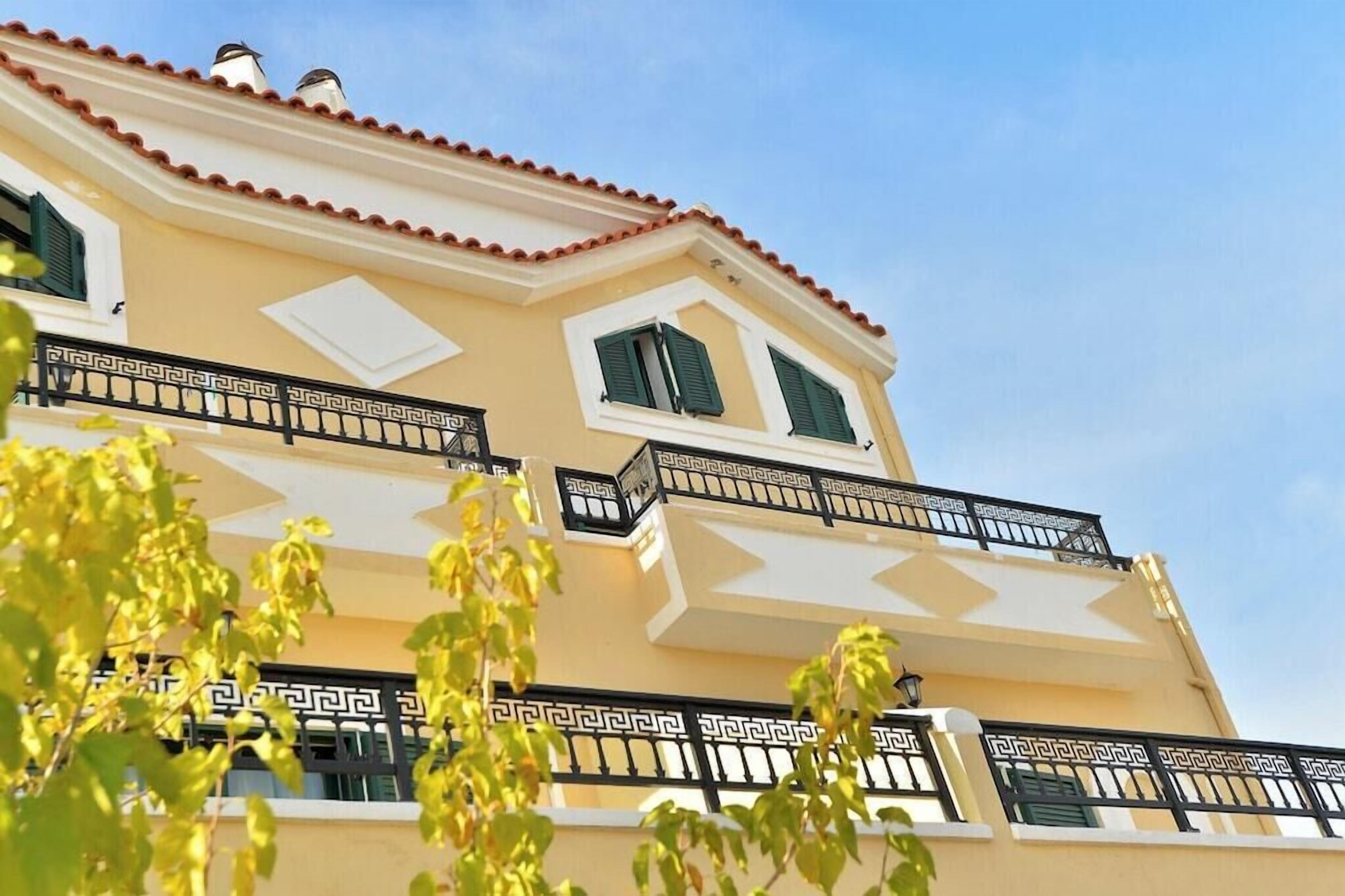 Um edifício de vários andares com varandas, telhado com telhas e céu claro.