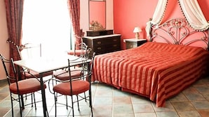 Una habitación con cama, una mesa con sillas, un espejo y una ventana con cortinas.
