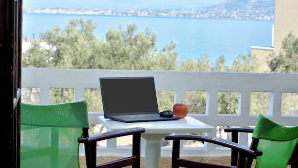 Un balcón con una laptop, una manzana y una silla.