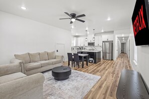 Ein modernes Wohnzimmer mit einer Couch, einem Couchtisch und einem Essbereich mit Stühlen und einem Tisch.