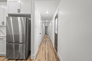 Eine Küche mit weißen Schränken, einem Edelstahlkühlschrank und Holzboden.