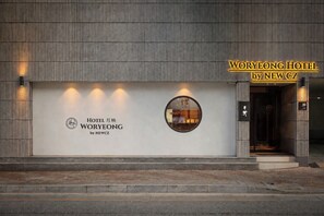 A hotel entrance with a modern facade, a prominent sign for WORYEONG HOTEL by NEWCZ, and a circular window reflecting the interior. - Woryeong Hotel By NewCZ (Andong)